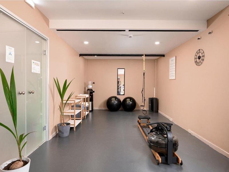 Kleiner Fitnessraum mit Rudergerät, Gymnastikbällen und Pflanzen in einem modernen Innenraum.