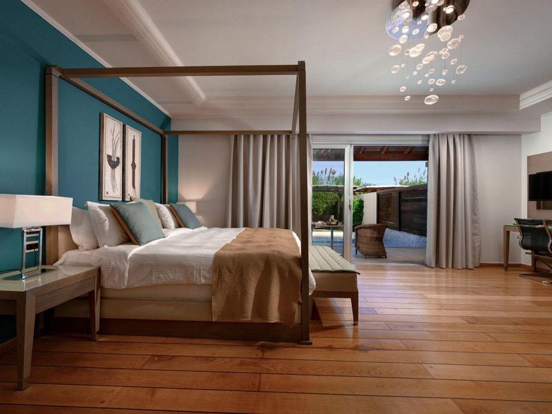 Elegantes Hotelzimmer mit Himmelbett, Holzboden und Zugang zu Terrasse mit Blick auf den Garten.