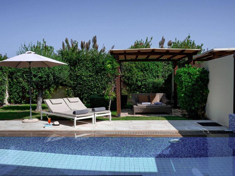 Moderner Außenpool mit Liegestühlen, Sonnenschirm und überdachtem Sitzbereich in Gartenumgebung