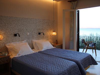 Helles Schlafzimmer mit zwei Einzelbetten, Lampen an der Wand und Balkon mit Meerblick.