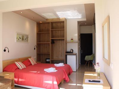 Hotelzimmer mit zwei Einzelbetten, roten Bettdecken, Holzregal und kleinem Kühlschrank.