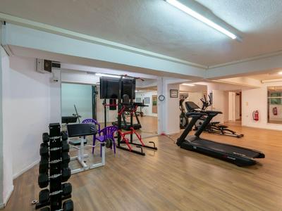 Moderner Fitnessraum mit Trainingsgeräten, Laufband und Hanteln in hellem Raum