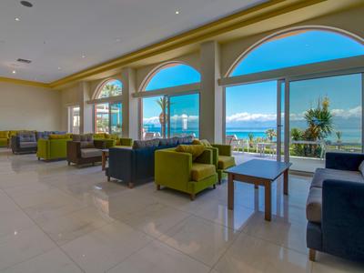 Großer, heller Loungebereich mit Sesseln und Blick auf die Terrasse und das Meer.