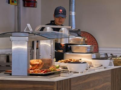 Buffet mit Pizza, Brötchen und verschiedenen Beilagen in einem Hotelrestaurant.