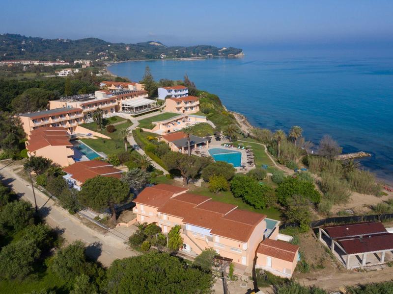 Seaside resort with multiple buildings and pools surrounded by greenery and ocean views.