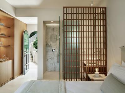 Modernes Schlafzimmer mit Holzregal, glassierter Dusche und Holzgitter als Raumteiler.