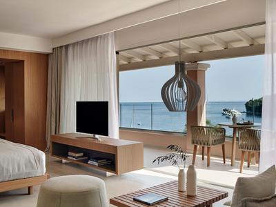 Helles Wohnzimmer mit moderner Einrichtung und großer Glasfront mit Blick aufs Meer und Terrasse.