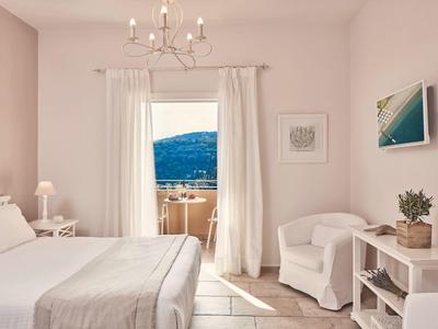 Helles, gemütliches Schlafzimmer mit Weiß- und Beigetönen, Balkon und Meerblick.