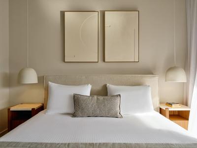 Modernes Schlafzimmer mit Doppelbett, weißer Bettwäsche und minimalistischer Dekoration.