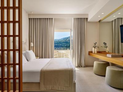 Modernes Hotelzimmer mit großem Bett und Blick auf die Berge durch das Fenster.