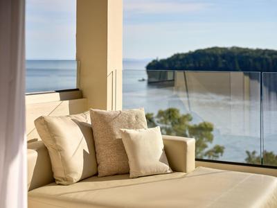 Gemütliche Sitzgelegenheit mit Kissen auf der Terrasse mit Meerblick und Insel im Hintergrund.