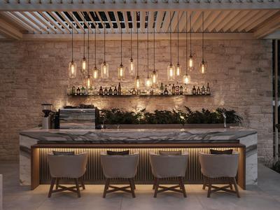 Moderní bar v hotelu s vysokými židlemi, elegantním osvětlením a cihlovou zdí.