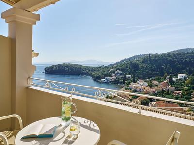 Balkon se stolem a židlí s výhledem na moře a pobřeží v rekreačním prostředí.