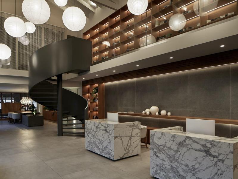 Moderner Innenraum mit schwarzer Wendeltreppe, hängenden Kugelleuchten und marmorierten Sitzwürfeln.