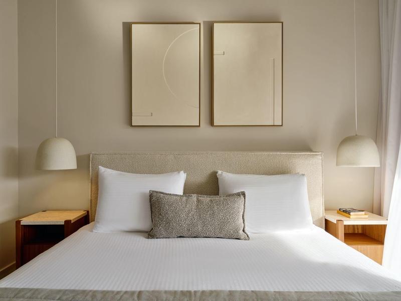 Modernes Schlafzimmer mit Doppelbett, weißer Bettwäsche und minimalistischer Dekoration.