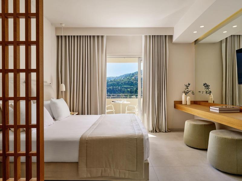 Modernes Hotelzimmer mit großem Bett und Blick auf die Berge durch das Fenster.