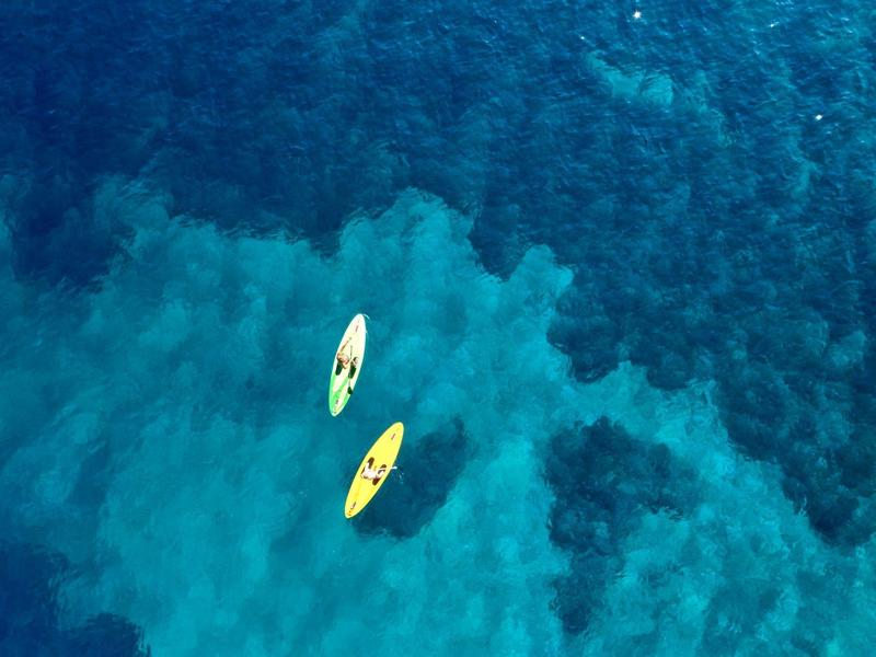 Zwei bunte Kajaks schweben auf klarem, tiefblauem und türkisfarbenem Wasser, Luftaufnahme.