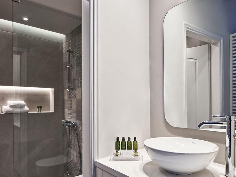 Modernes Badezimmer mit großer Spiegel, weißem Waschbecken und Glasdusche mit LED-Beleuchtung.