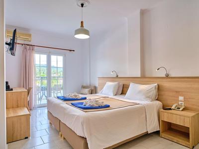 Helles Hotelzimmer mit zwei Betten, Balkon und Fernseher an der Wand.