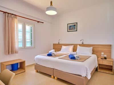 Helles Schlafzimmer mit Doppelbett, Nachttischen, Fenster mit Vorhängen und minimalistischer Dekoration.