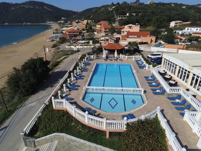 Blick auf ein Hotel mit Pool, Liegestühlen und einem langen Sandstrand in der Nähe.