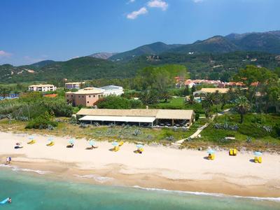Strand mit Sand, Sonnenschirmen, türkisfarbenem Meer und grünen Hügeln im Hintergrund.