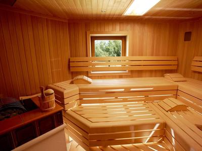 Helle Holzsauna mit mehrstufigen Sitzbänken und kleinem Fenster für Außenblick.