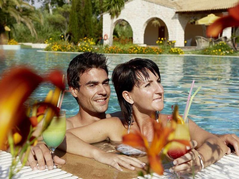 Ein Paar entspannt im Pool, umgeben von grünen Pflanzen und blühenden orangen Lilien.