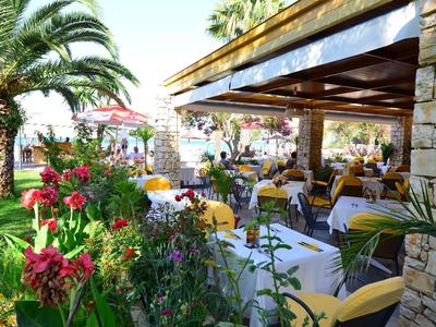 Gemütlicher Außenbereich eines Restaurants mit gedeckten Tischen und grüner, blühender Umgebung.