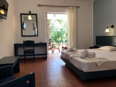 Helles Hotelzimmer mit Doppelbett, Schreibtisch und Zugang zu einem Balkon mit Sitzgelegenheiten.