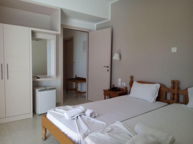 Ein einfaches Hotelzimmer mit zwei Einzelbetten, einem Kleiderschrank und einem Spiegel.