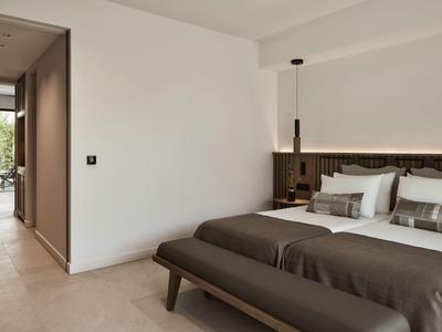 Modernes Hotelzimmer mit Doppelbett, braunen Holzmöbeln und Zugang zu einer Terrasse.