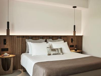 Modernes Hotelzimmer mit großem Bett, Holzpaneelen und minimalistischen Nachttischen.