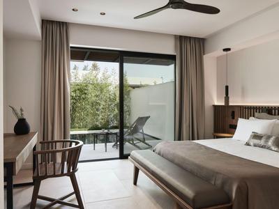 Modernes Hotelzimmer mit Doppelbett, Balkon und Blick auf grüne Pflanzen.
