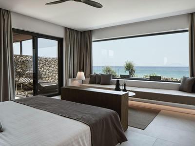 Modernes Hotelzimmer mit Doppelbett, Sitzbank, großem Fenster und Meerblick.