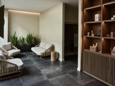 Moderner Hotel-Wartebereich mit weißen Sesseln, Pflanzen und Holzregalen.