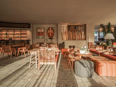 Area lounge accogliente dell'hotel con posti a sedere, luce calda e decorazioni murali.