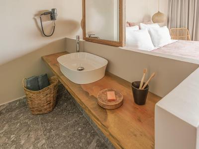Bagno moderno con lavabo in legno e pavimento in marmo grigio in una camera d'hotel.