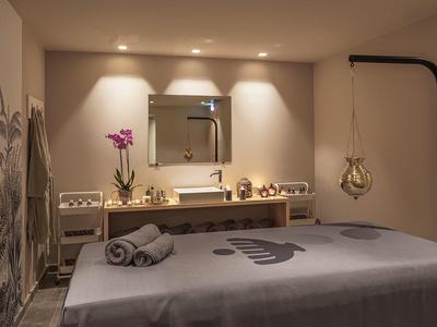 Stanza trattamenti tranquilla con lettino da massaggio, illuminazione soffusa e decorazioni rilassanti.