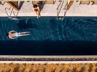 Vista aerea di una piscina rettangolare con due persone, una che nuota, l'altra seduta al bordo.