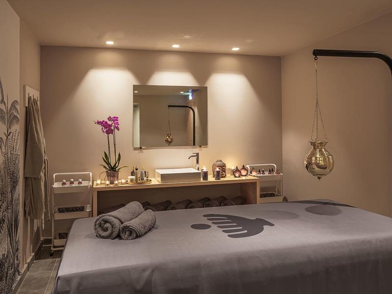 Stanza trattamenti tranquilla con lettino da massaggio, illuminazione soffusa e decorazioni rilassanti.
