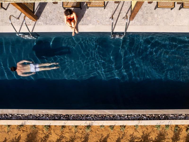 Due persone si rilassano in una piscina lunga e stretta accanto a una terrazza con sedie