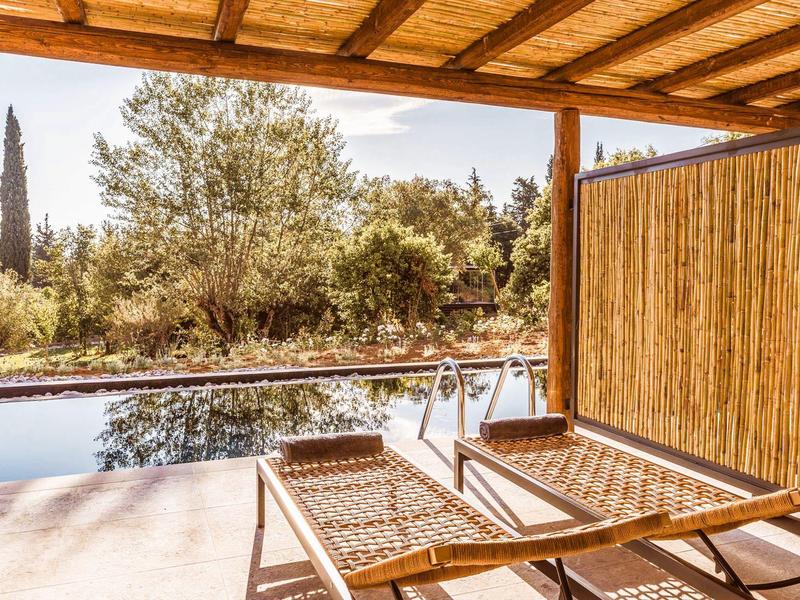 Terrazza coperta con sedie a sdraio con vista su piscina e alberi.