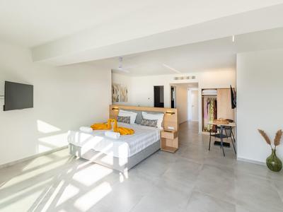 Helles, modernes Schlafzimmer mit großem Bett, grauen Fliesen und minimalistischer Einrichtung.
