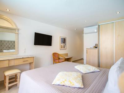 Helles Hotelzimmer mit Doppelbett, Tisch, Stuhl, TV und großem Spiegel an der Wand.