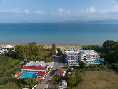 Hotelanlage mit Pool, Liegestühlen und direktem Zugang zum Sandstrand an ruhiger Meeresküste.