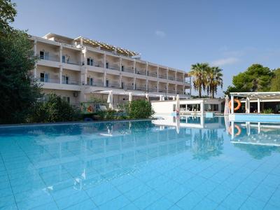Hotelgebäude mit mehreren Balkonen und großem Pool, umgeben von Palmen und blauem Himmel.