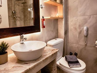 Modernes Badezimmer mit rundem Waschbecken, Toilette und Marmorwaschtisch in warmem Licht.