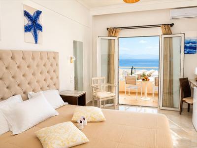 Helles Hotelzimmer mit Doppelbett und Balkon mit Blick auf das Meer.