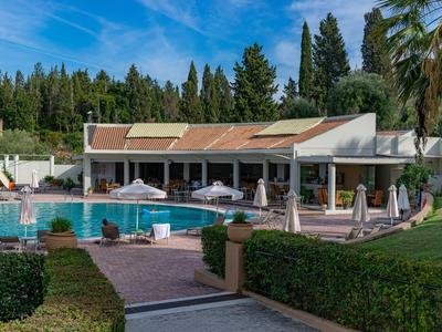 Moderner Hotelpool mit Sonnenschirmen, Liegen und umliegender Gartenanlage bei klarem Himmel